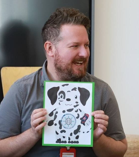 A teacher holding up a picture of Dilon during a lesson